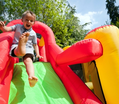 Small boy jumping down the slide on an inflatable bouncy castle Small boy jumping down the slide on an inflatable bouncy castle